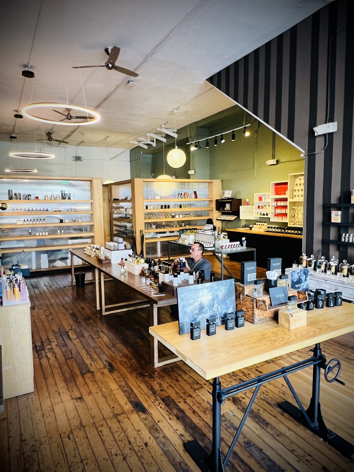 Ken evaluating a fragrance — scent strip in hand, notebook open, bottles lined up on the counter
