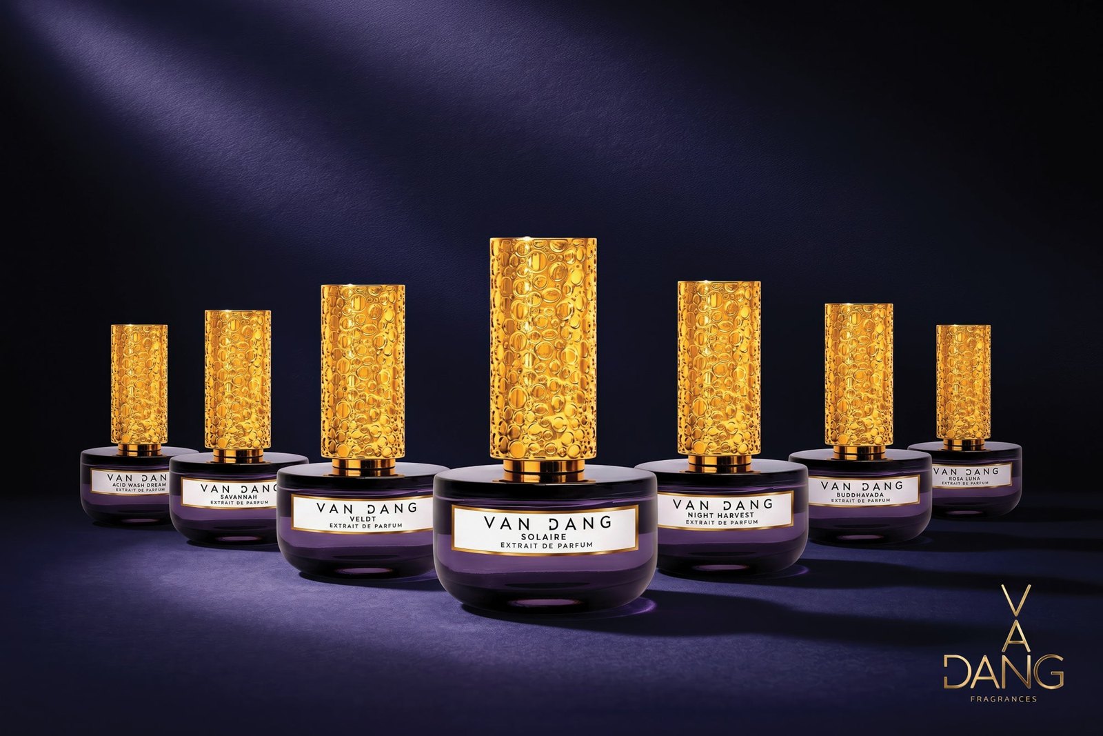 Seven Van Dang extrait de parfum bottles with gold caps on a deep purple backdrop